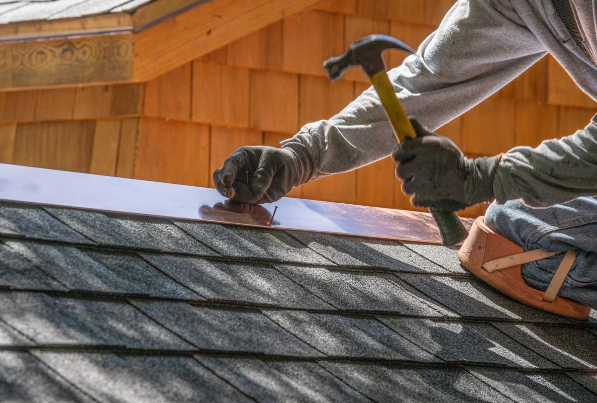roofer nailing on roof flashing on single roof